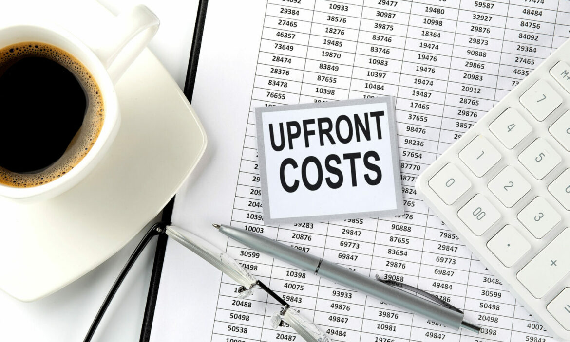 UPFRONT COSTS text on sticky on the chart with coffee,pen and calculator Upfront cost