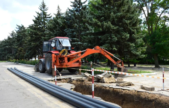 Laying of urban district heating plastic pipes lying next to the trench. A trench dug by a tractor