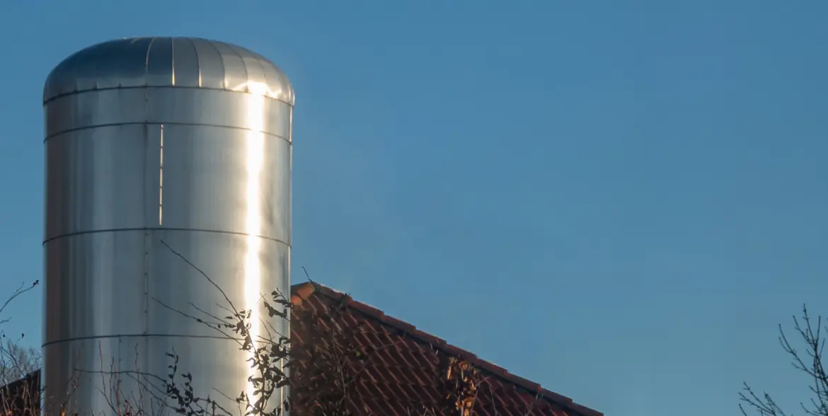 District heating system installation in a residential area, showing a metal cylindrical thermal storage tank