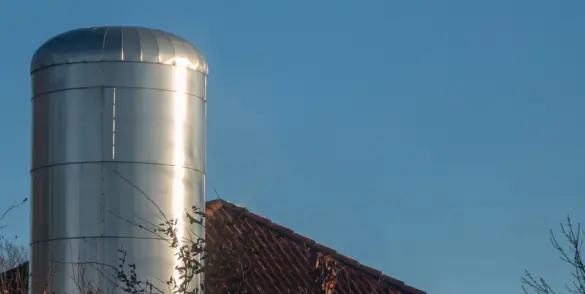 District heating system installation in a residential area, showing a metal cylindrical thermal storage tank